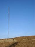 Tall communications transmitter on a winter hill top against a clear sunny blue sky