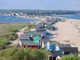 Row of colorful beach huts or cabins for vacations and getaways lining the Dorset seashore, high angle landscape view