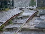 Damaged bent tracks in an old abandoned slate mine, low angle view showing the abrupt curve