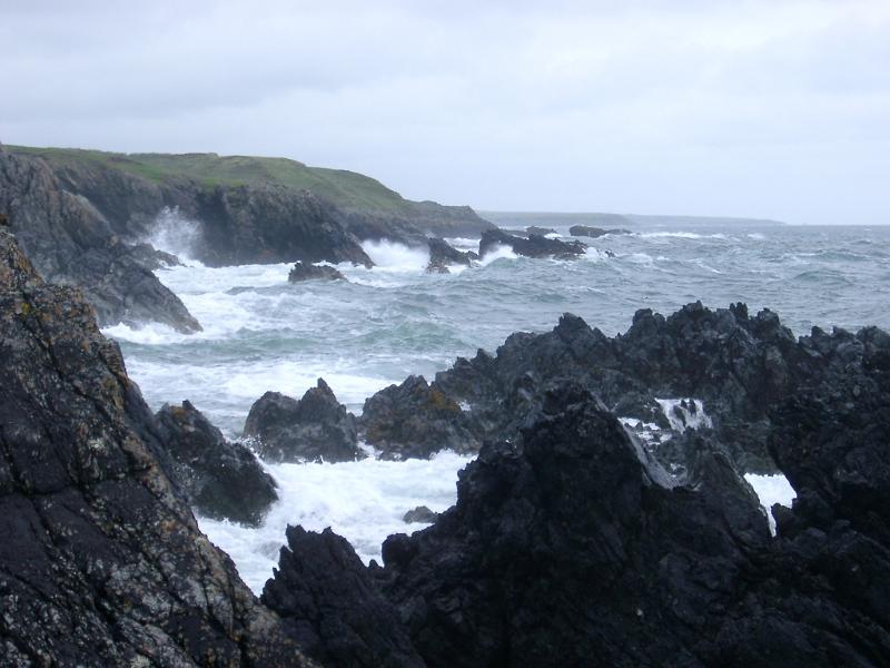 Stormy sea with waves pounding a rocky coastline on an overcast misty day