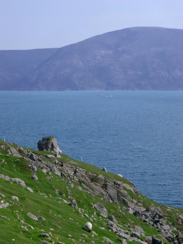 Beautiful Coastal Scene with Grassy Cliff, Tranquil Sea and Huge Mountains View in Scotland.