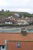looking over tiled cottage roof tops to the lower harbour and rows of cottages with the abbey and church on the hill
