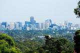 A panoramic view from the lush forest of the Adelaide hills over the tall skyscrapers of the city centre.