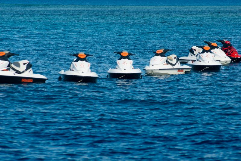 Jet skis moored in a line on open ocean waiting to be taken out on the water for personal enjoyment and recreation