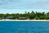 Bounty Island resort, Fiji, on an idyllic tropical island with tourist visible on the sandy beach in front of the buildings