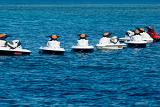 Jet skis moored in a line on open ocean waiting to be taken out on the water for personal enjoyment and recreation