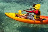 Kayaker in a small single kayak or canoe paddling in clear tropical water enjoying his summer vacation