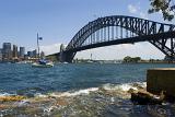 A panoramic view of the Sydney harbour bridge, boats and city on a beautiful, clear, blue sunny day.