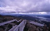 Lookout platform on Mount Wellington, Tasmania overlooking the Derwent River estuary and city of Hobart on a grey overcast day with a tourist at the viewing telescope