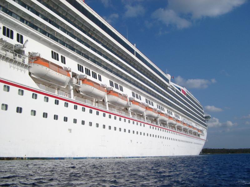 Side view of a cruise ship looking down the length of the hull with decks of cabins and life boats strung along the side conceptual of a voyage, travel and vacation