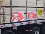 Close Up of Timber Truck Hauling Load of Timber with Promotional Signs