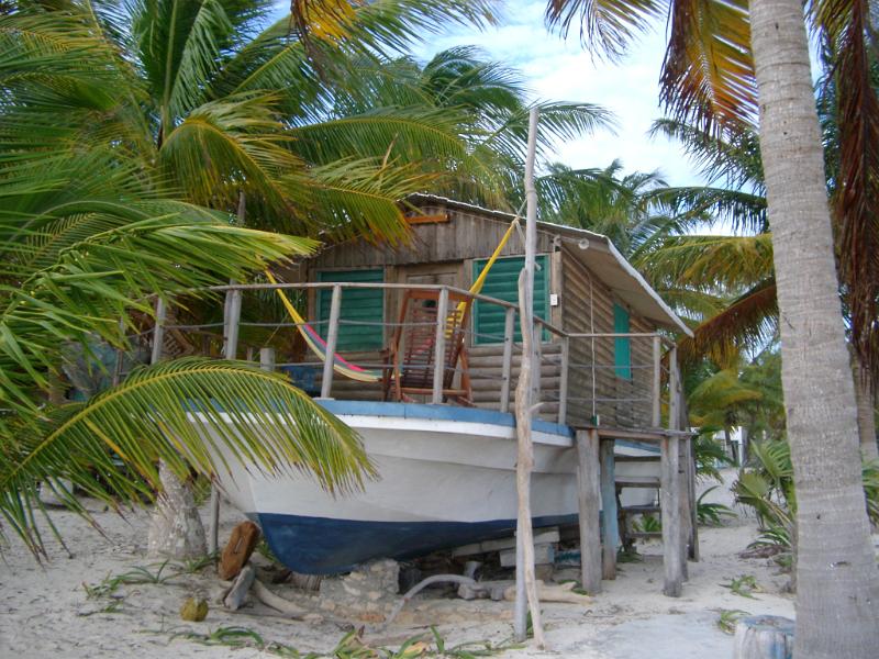 Wooden log cabin houseboat in Mexico sited on the golden sand of a tropical beach amidst palm trees