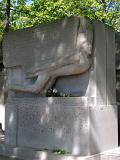 Tomb of Oscar Wilde Grave at Pere-Lachaise Cemetery. Isolated on Green Leafy Trees Background.