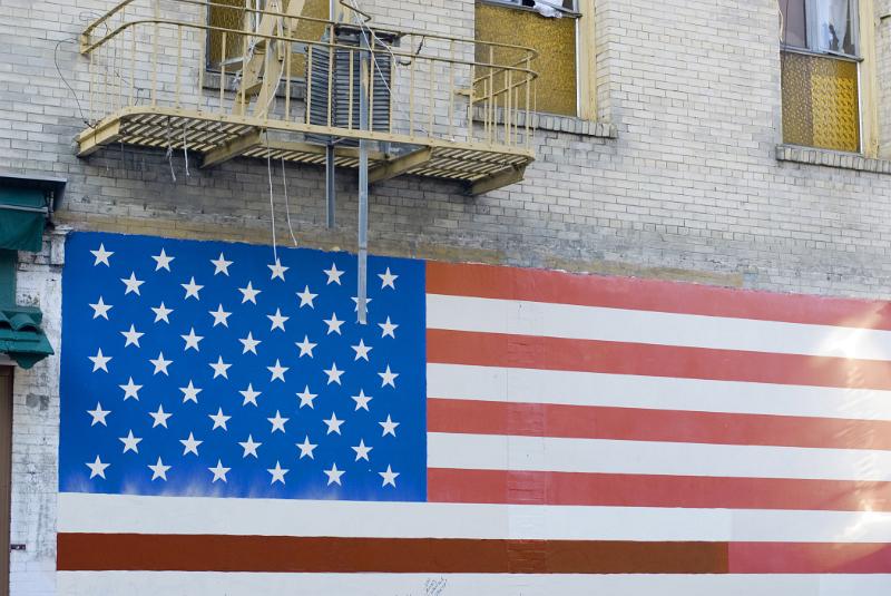 Patriotic wall mural of the Stars and Stripes American national flag painted on the exterior wall of an old building
