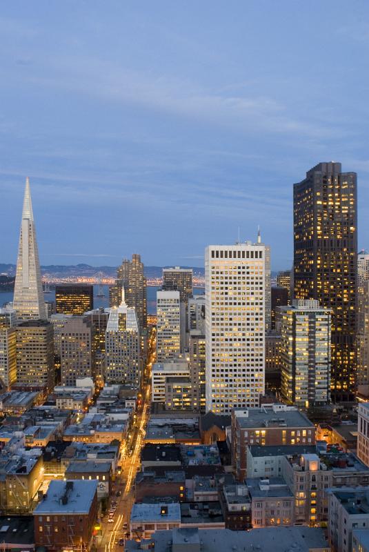 San Francisco, California, at night with a view over rooftops to the CBD with its modern skyscrapers and high-rise buildings illuminated at twilight