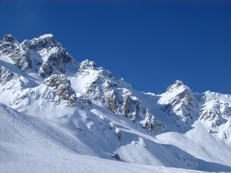 Snow covered rugged mountain peaks in France under a clear crisp blue winter sky in a spectacular landscape